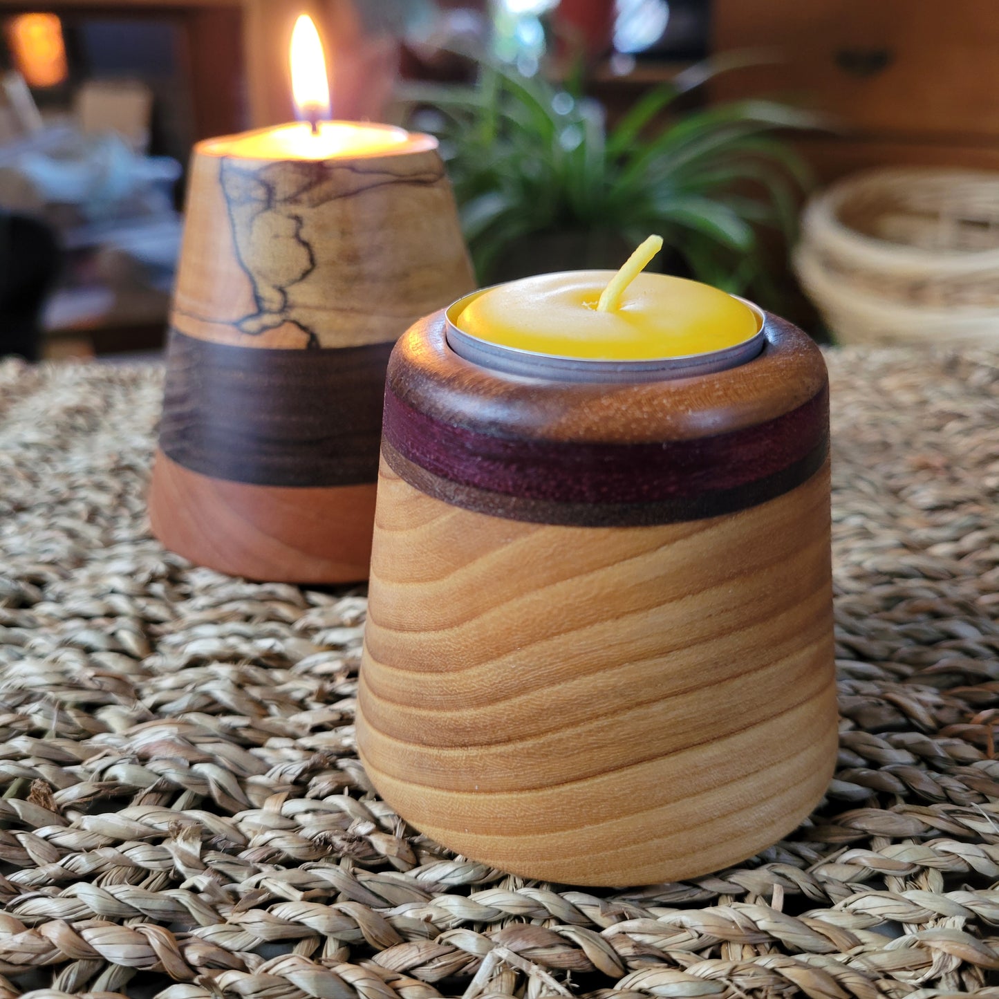 Wooden candle holders with candles on a woven surface