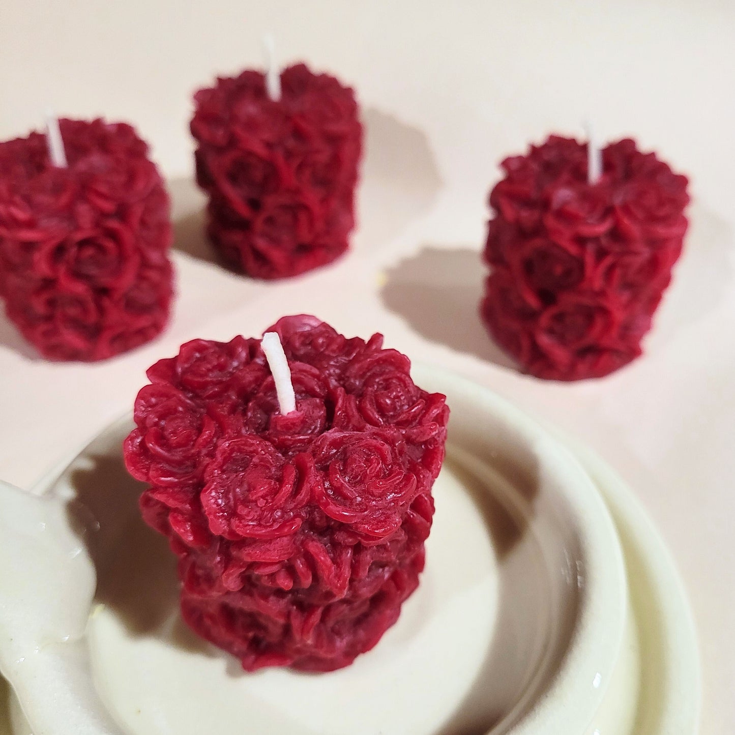 Ruby red rose-covered votive candles on a white ceramic holder