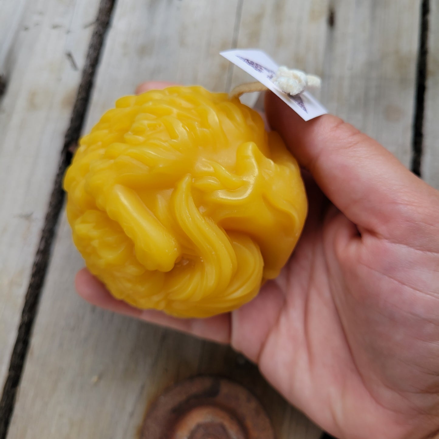 Cozy sleepy fox beeswax candle, side view, held in a hand.