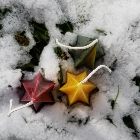 star shaped candles sitting in snowy background