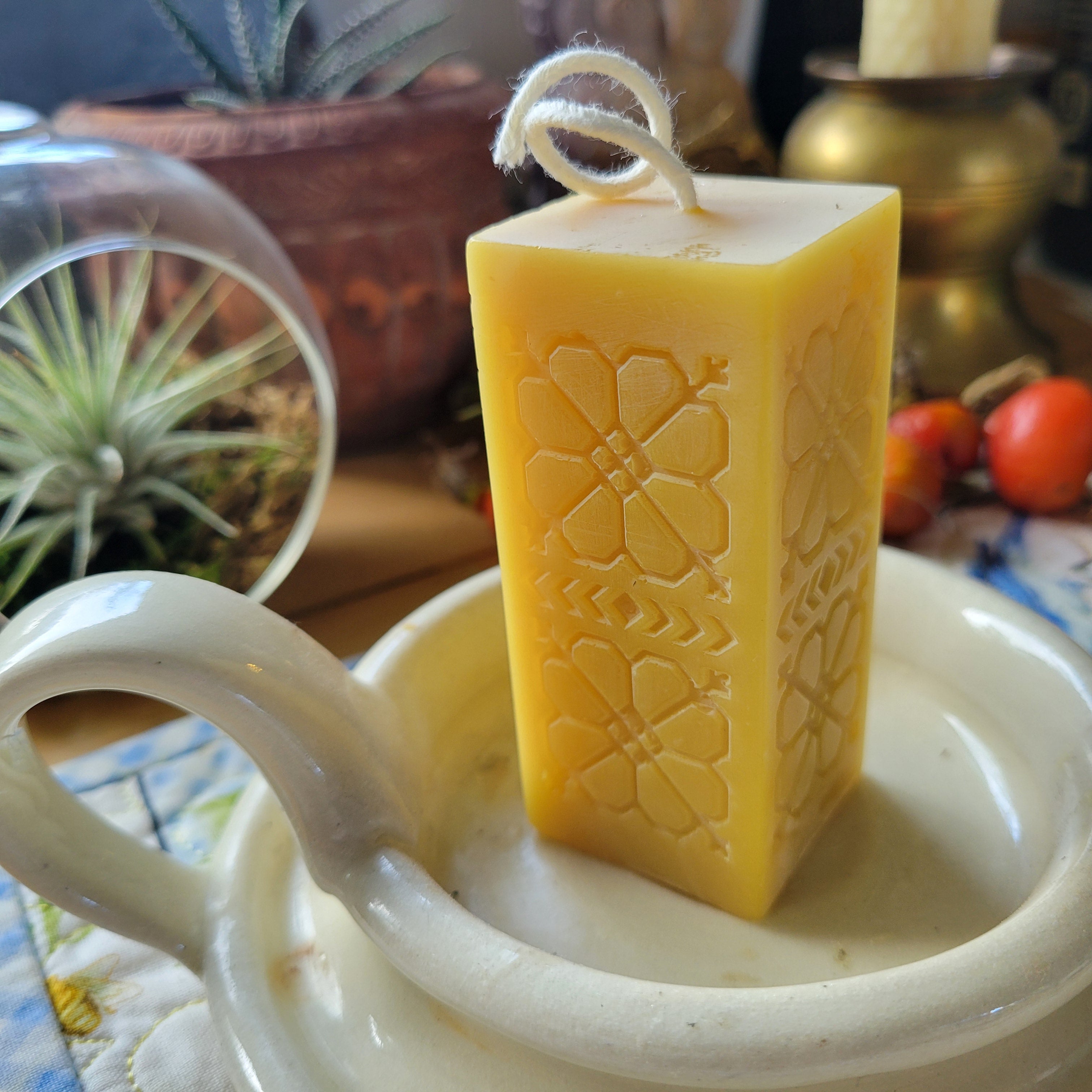 beeswax candle sitting in a pottery candle holder