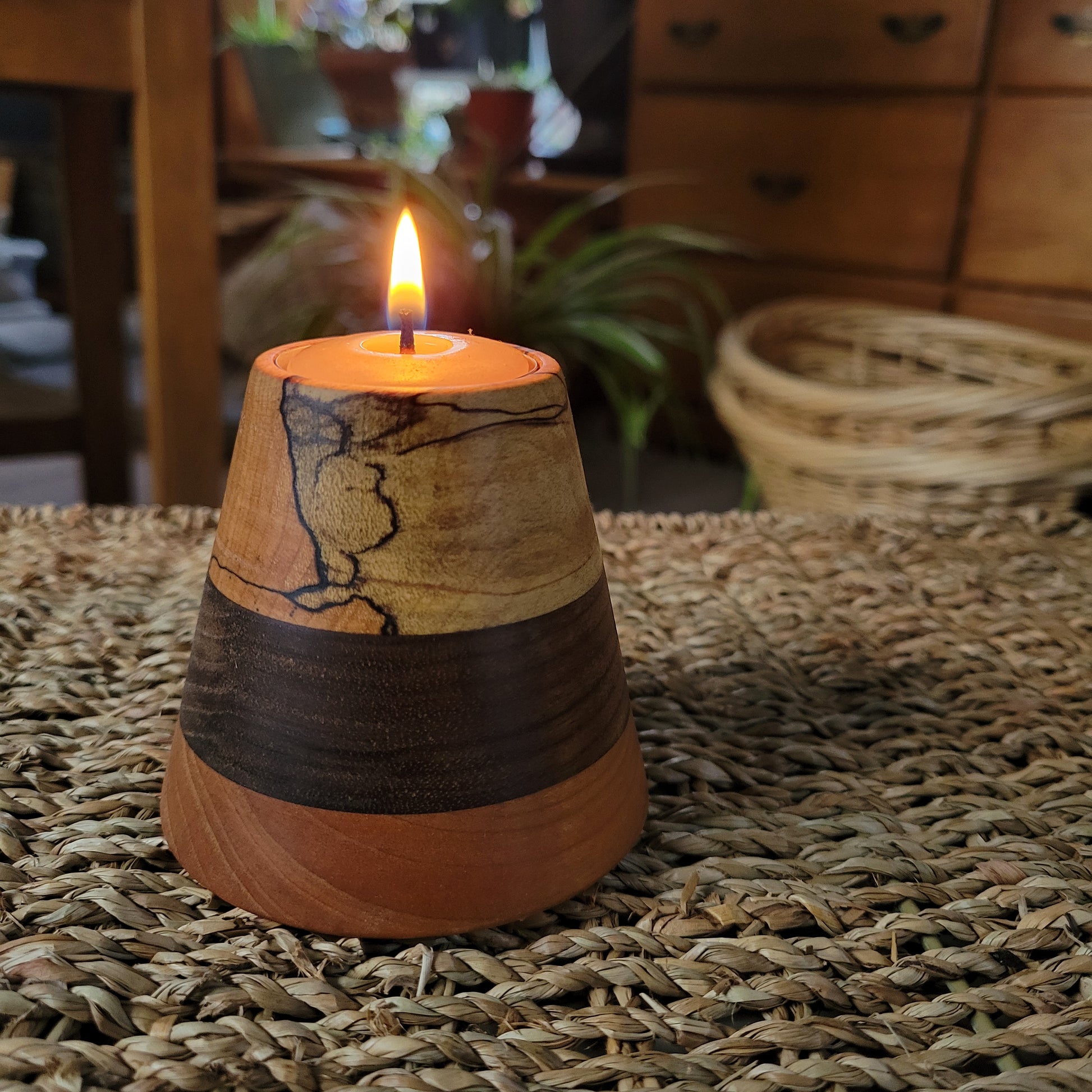 wooden tealight holder with lit tealight  sitting on a wicker table