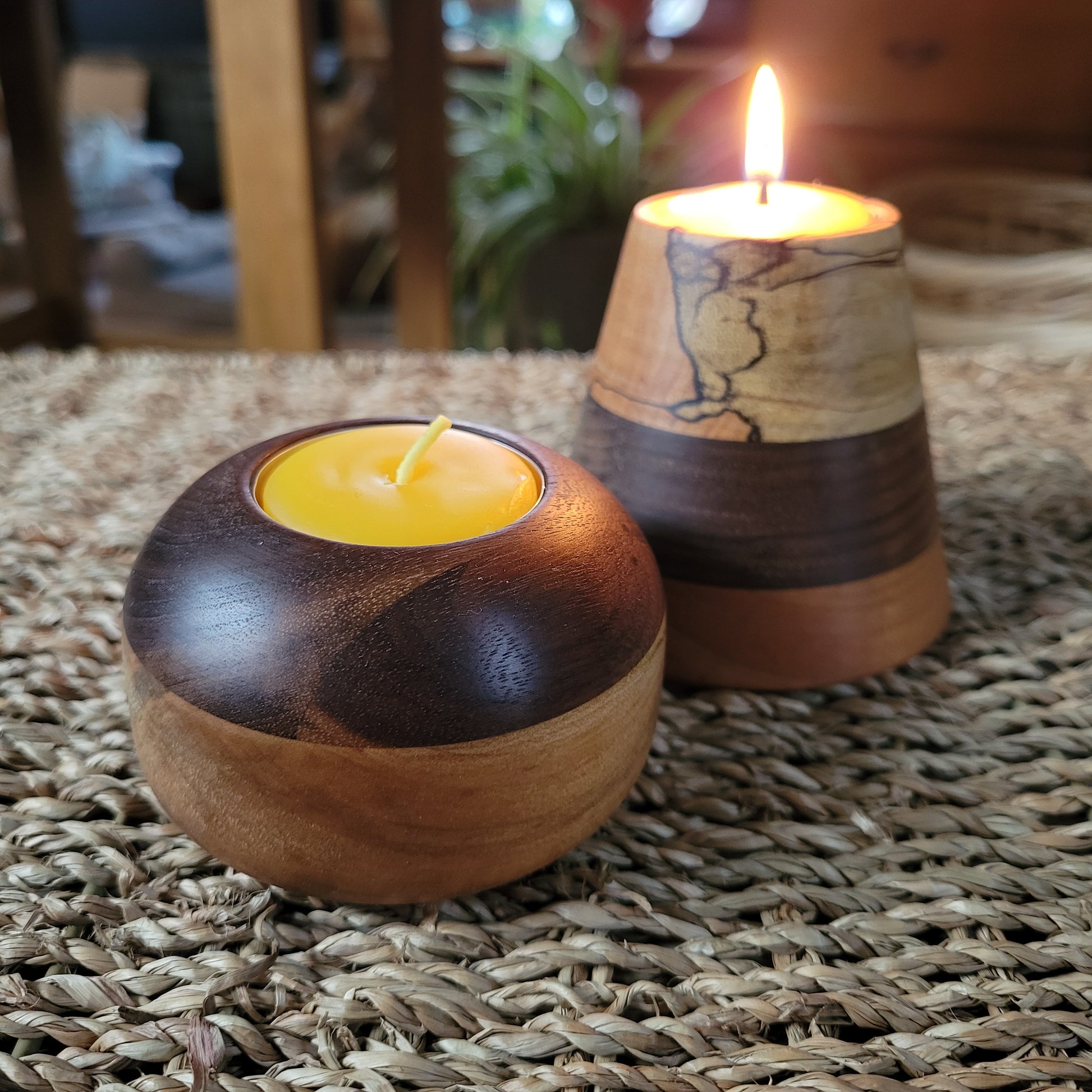Two wooden candle holders with candles on a textured surface.