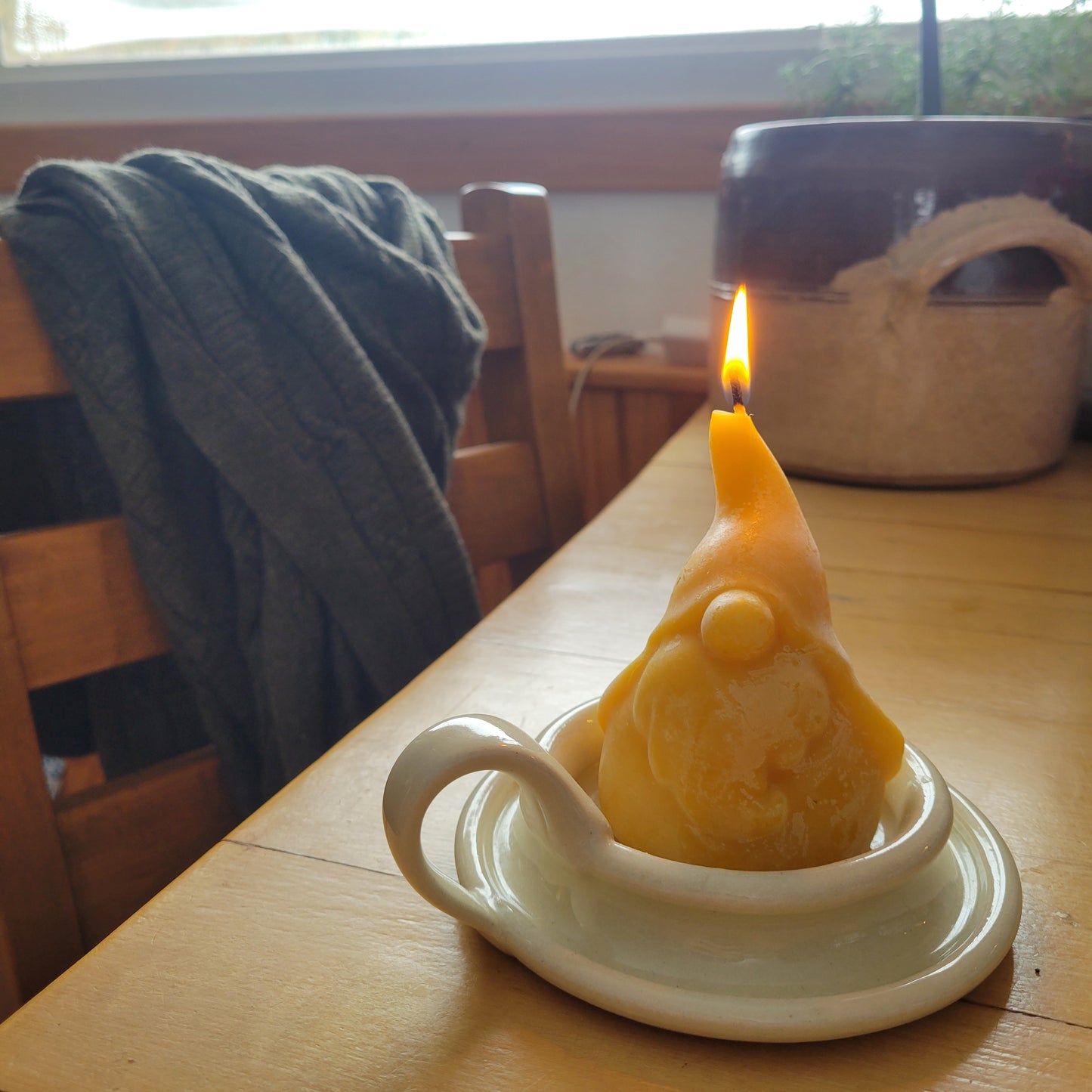 Grimble Grumble beeswax gnome candle lit in a white pillar candle plate