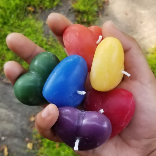 Hand holding six colorful heart-shaped candles on a natural background