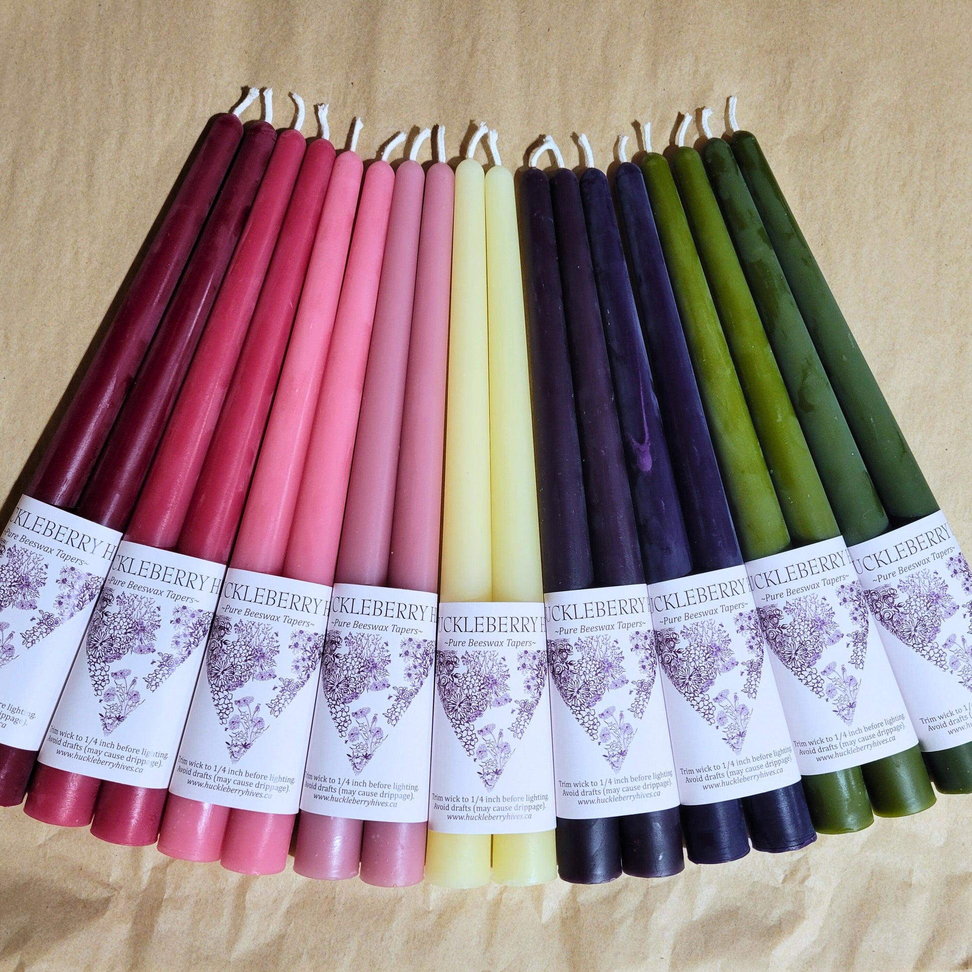 Assorted colored taper candles with labels on a beige background