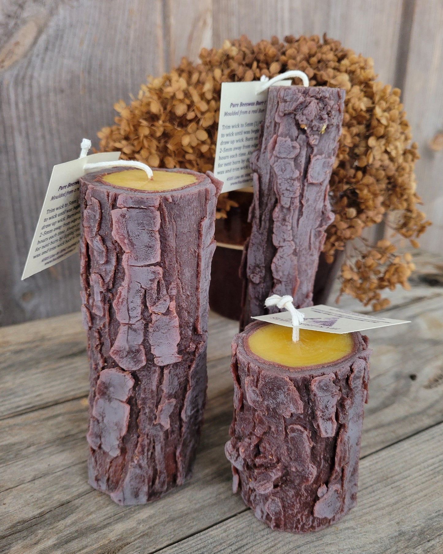 Three rustic log-shaped candles on a wooden surface