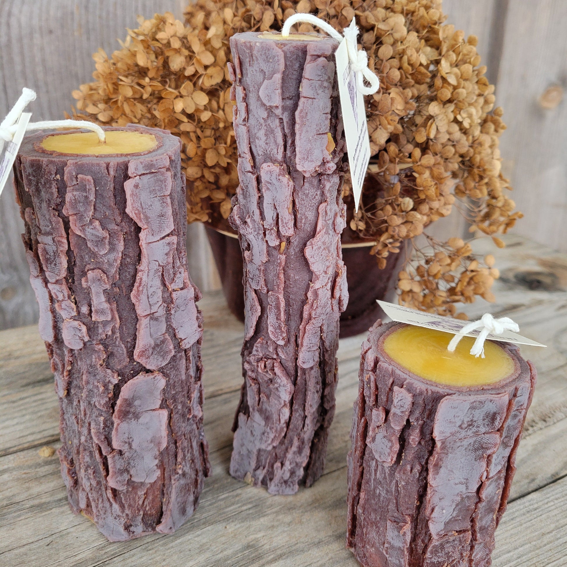 Three log-shaped candles with wicks on a wooden surface