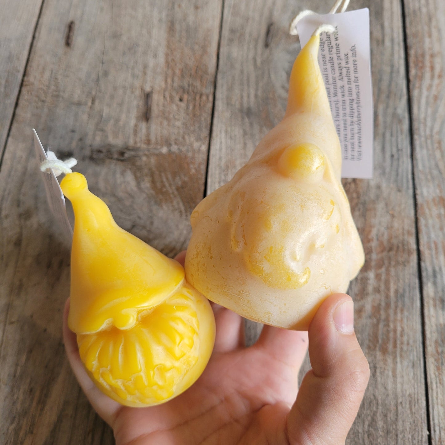 hand holding two gnome candles with a wooden background; showing difference between two styles: Grimble Grumble and Bumble Crumble