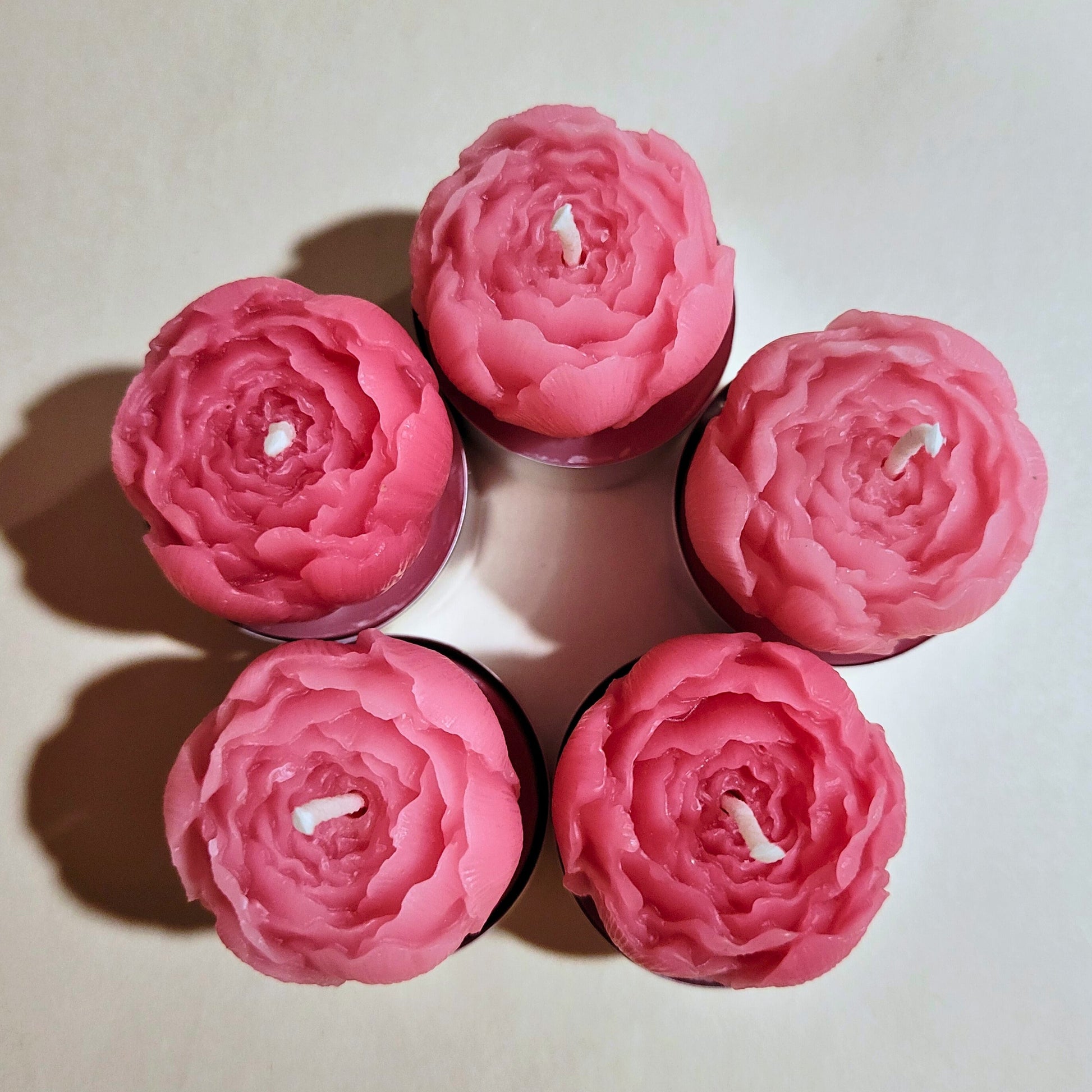 Five pink peony-shaped candles against a light background