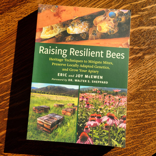 Book titled 'Raising Resilient Bees' on a wooden surface