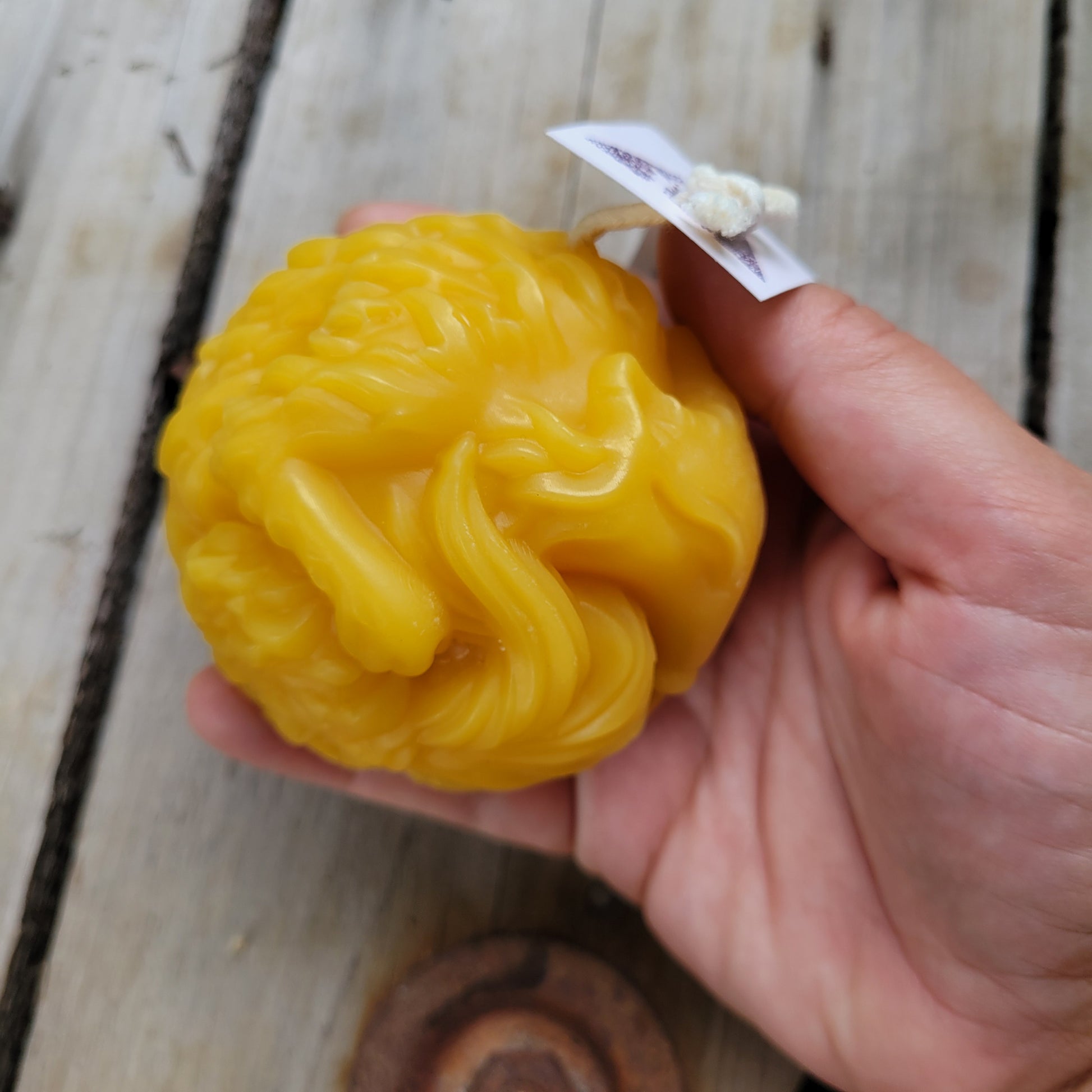 Cozy sleepy fox beeswax candle, side view, held in a hand. 