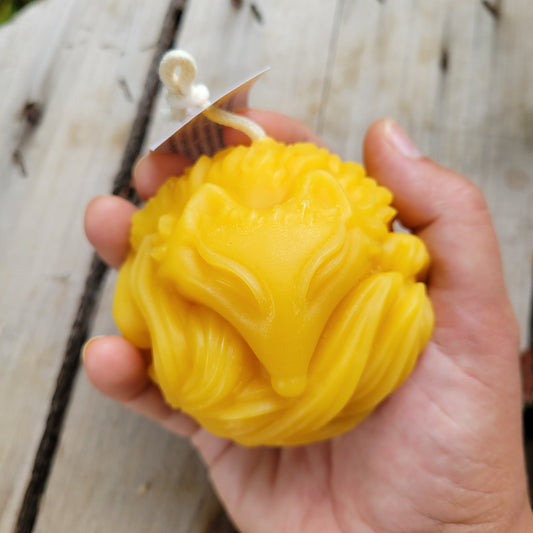 Sleepy fox beeswax candle held in a hand.
