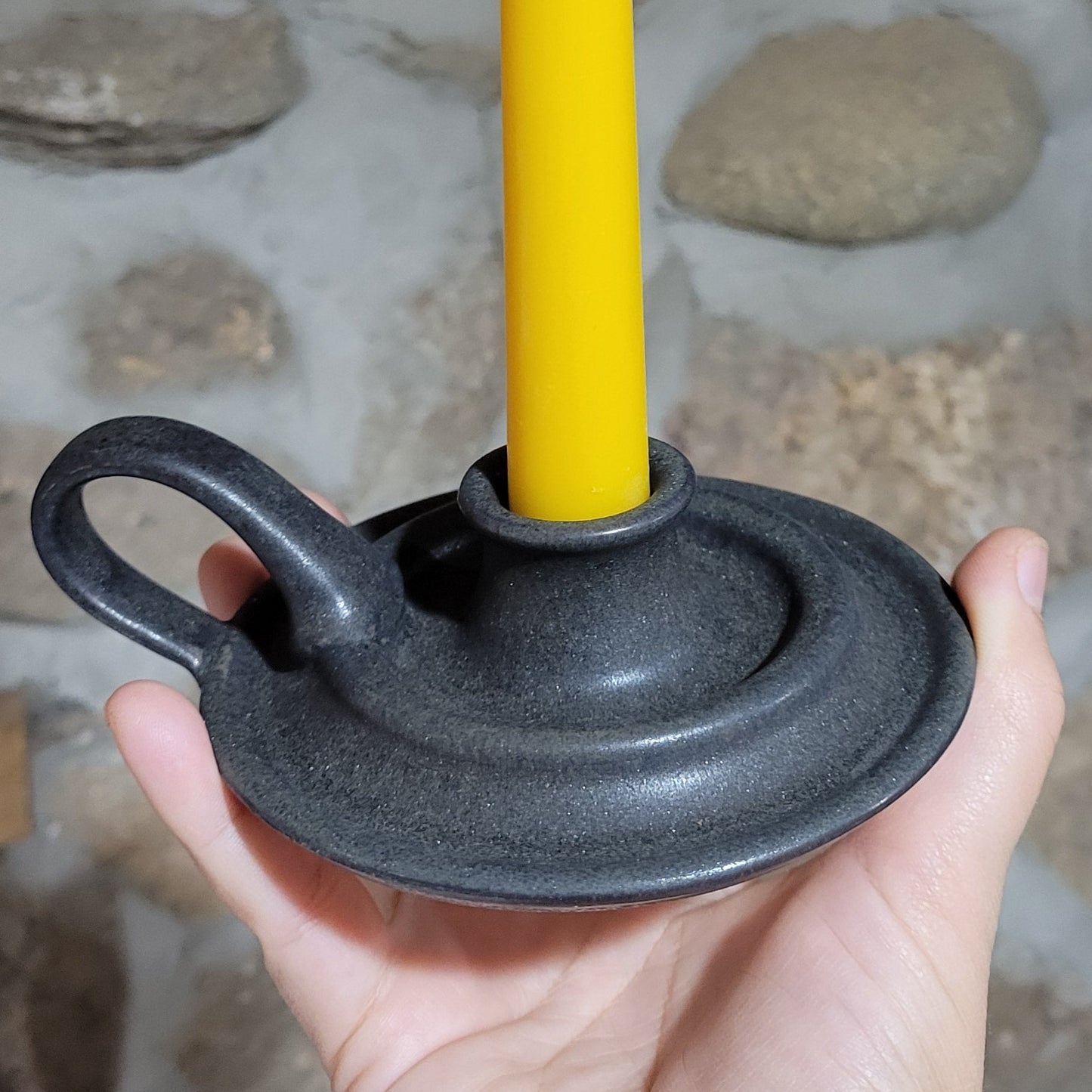gray pottery taper holder with a beeswax candlestick in it