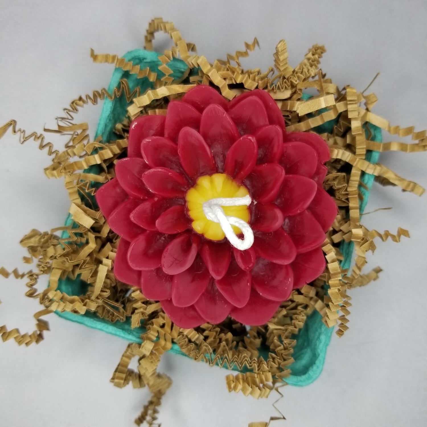 Red and yellow beeswax dahlia candle packaged in berry box