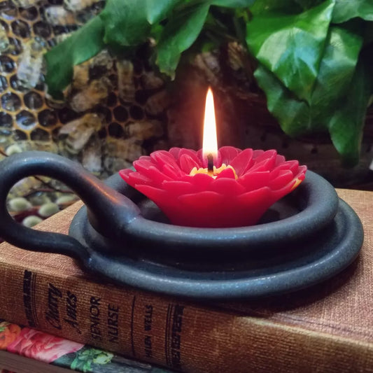 red beeswax dahlia candle burning in black candle holder